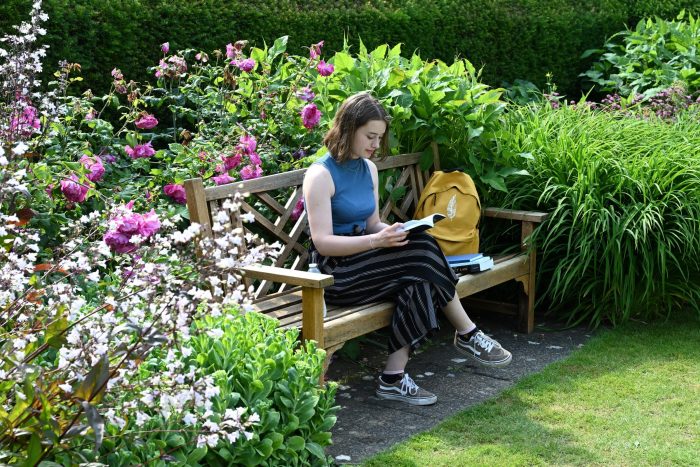 A woman sits reading surrounded by flowers