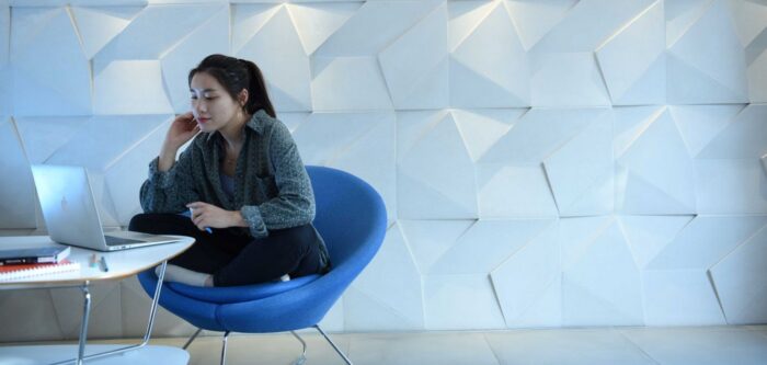 Student sitting with laptop in front of geometrically designed wall