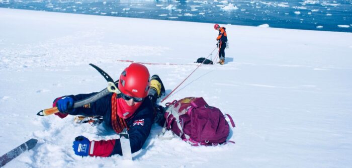 Researcher lying near snowy crevasse