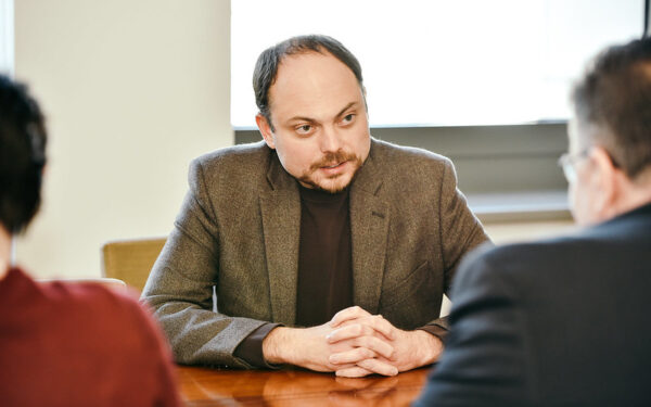 Vladimir Kara-Murza sat at a desk looking at two people opposite him. He has been awarded a Pulitzer Prize.