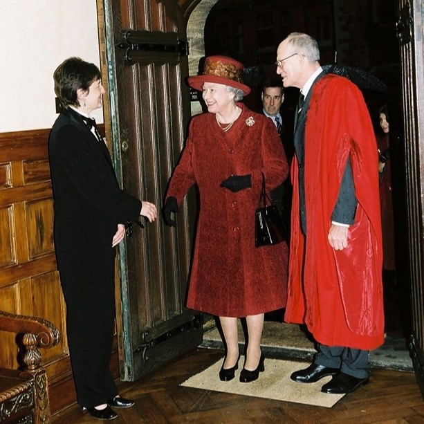 HM the Queen Elizabeth 2 is seen entering a building and shaking hands with the female butler who is greeting her.