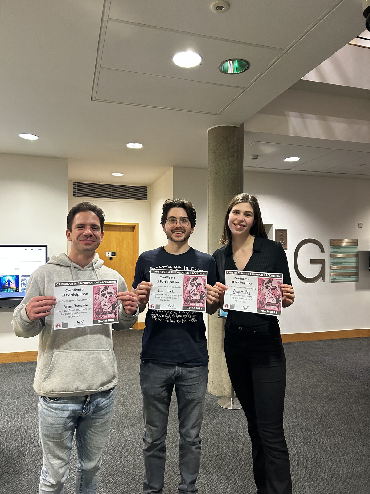Three students holding their winning certificates after their victory in a hackathon centred around misinformation