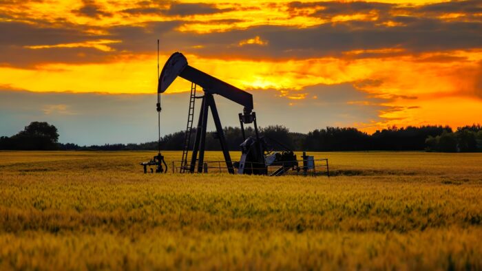 An oil derrick in a cornfield at sunset to represent COP 28 Climate Change conference