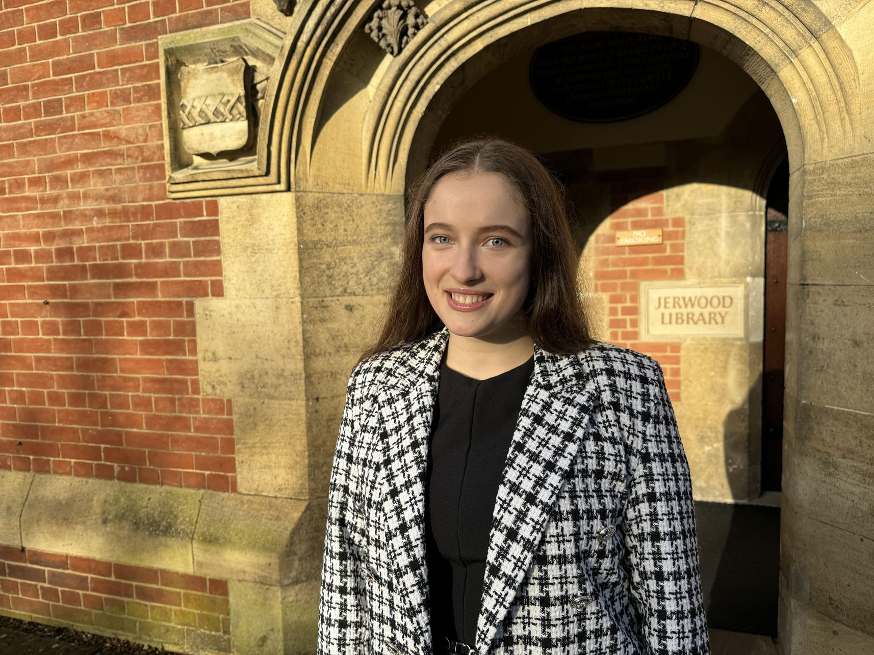 Anastasiia Koziak standing outside the entrance to the Jerwood Library, smiling at the camera