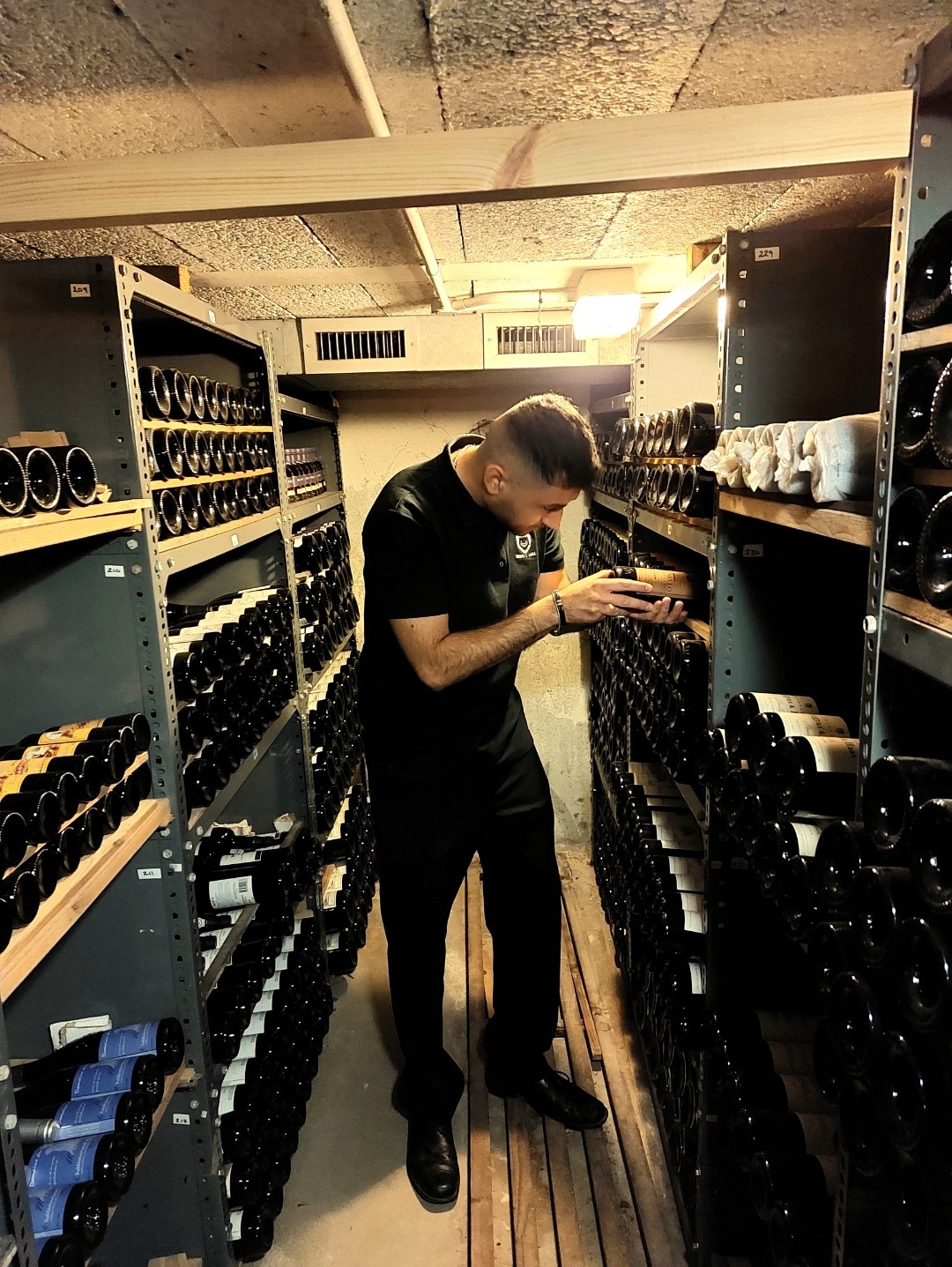 A passion for service: Gabriele Cirrottola in a wine cellar putting bottles in the racks. He is the new butler at Trinity Hall, Cambridge