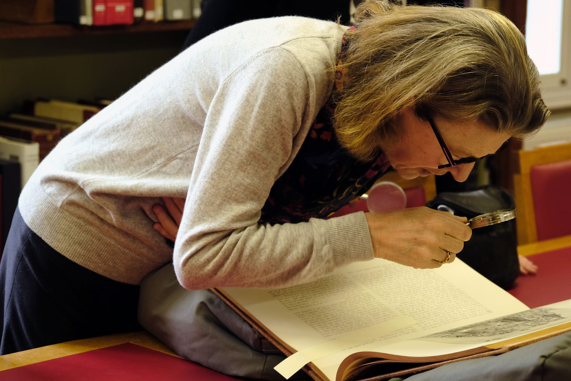 The Master inspecting a book with a magnifying glass