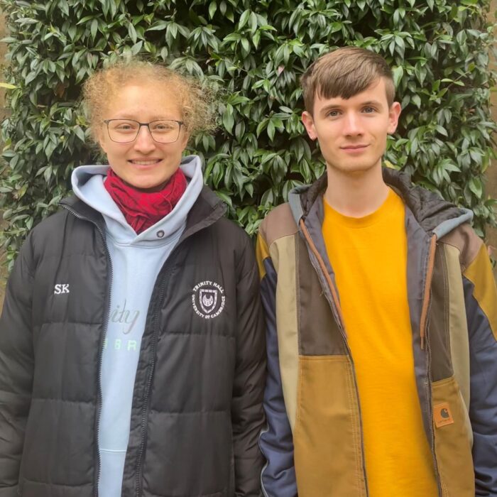 Sumei and Jake stood next to each other in front of a green bush.