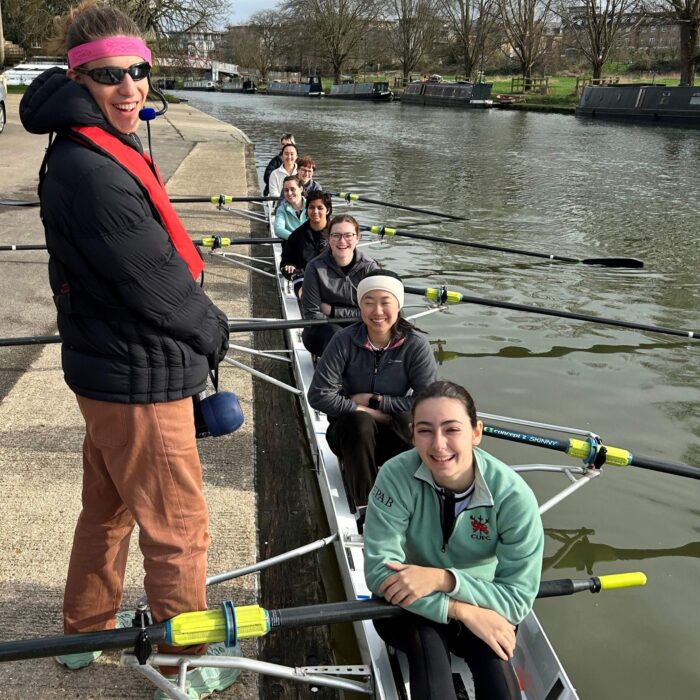 Smiling rowers and their cox on the River Cam. They are about to set off from Trinity Hall boathouse to race in the Lent Bumps 2024