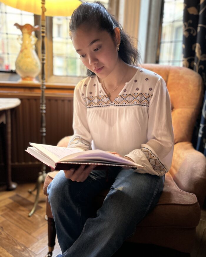 Poet Sam Elbahja sat in Trinity Hall holding her book of poems