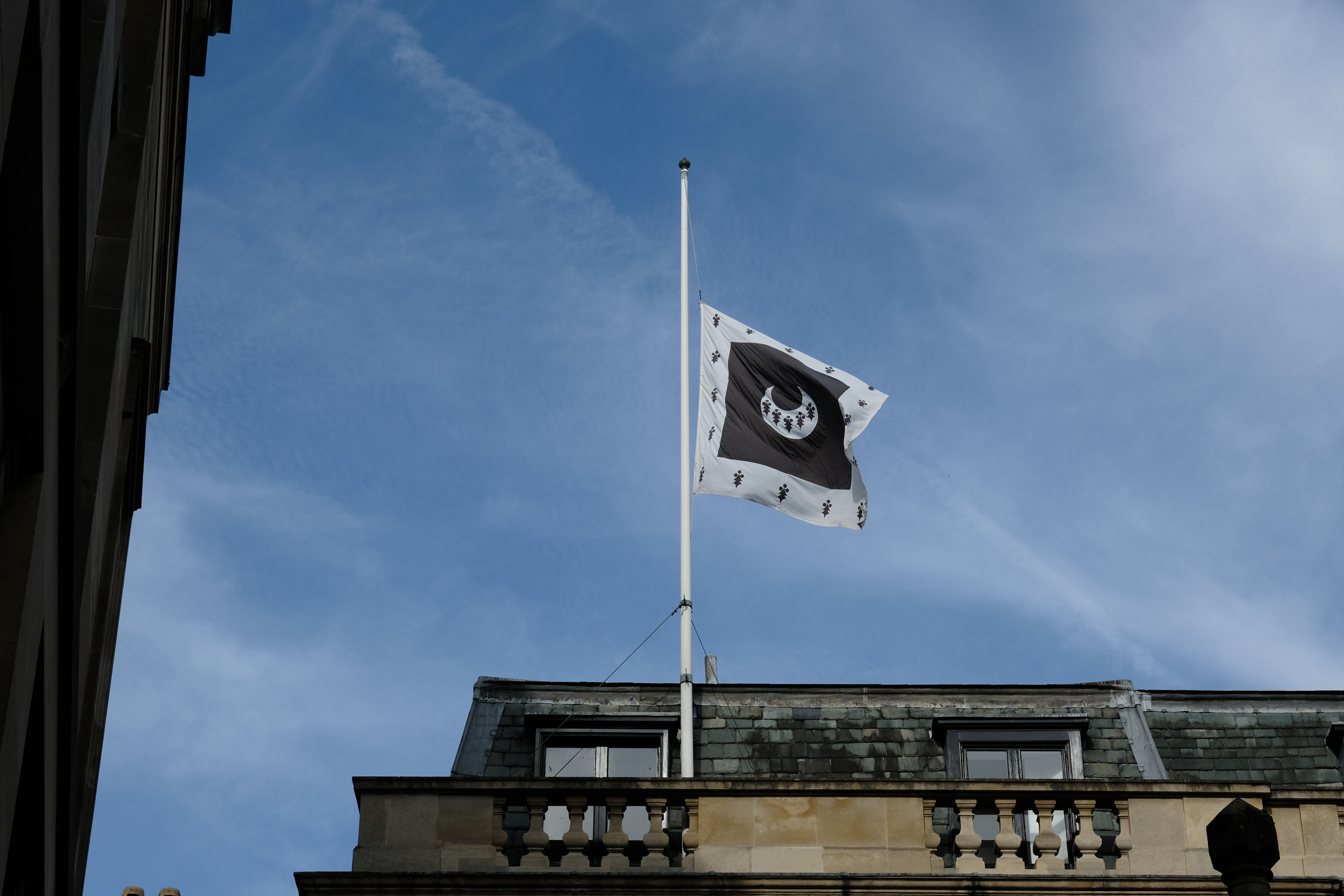 The Trinity Hall flag flying at half-mast in blue skies.