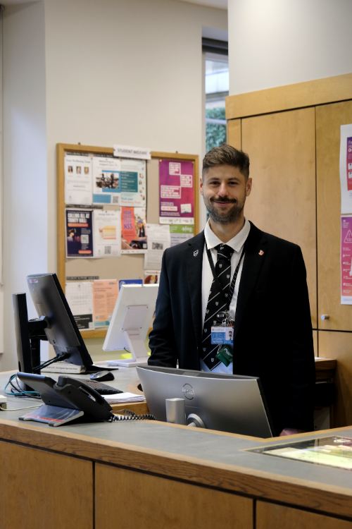 Porter Ivan standing at the desk in the Porters' Lodge.