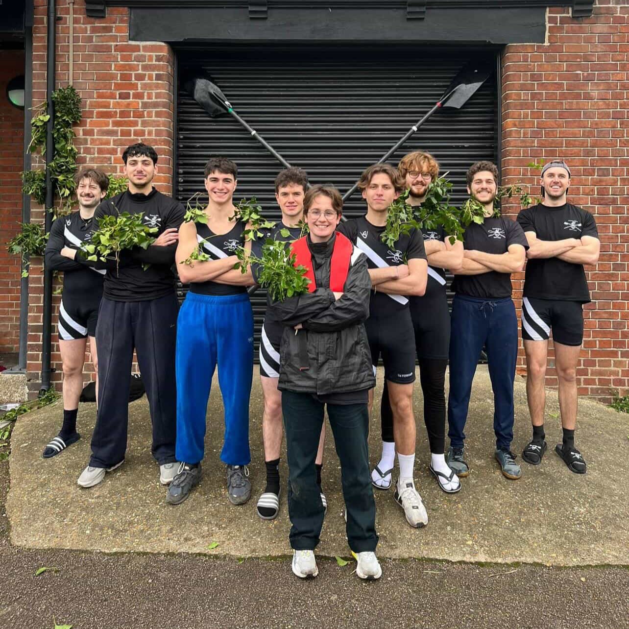 Men's Third boat standing in front of the Boathouse with foliage after a successful bump on day 5 of Lent Bumps.