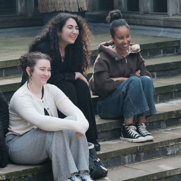 A group sitting on stone steps in a college courtyard.
