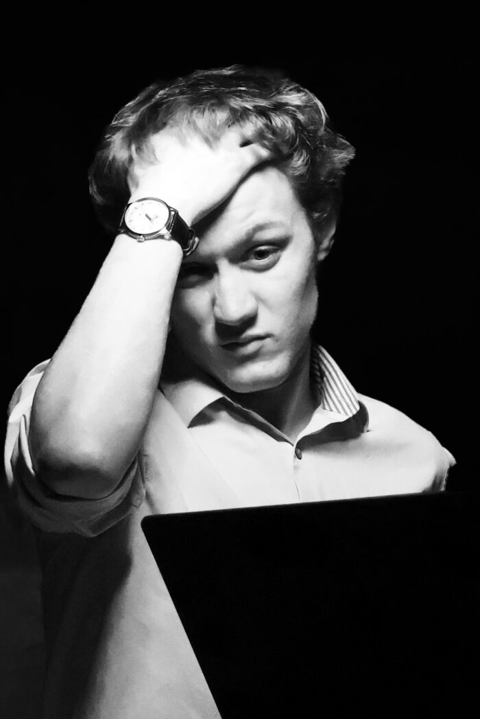 Black and white photo of man running his hand through his hair.