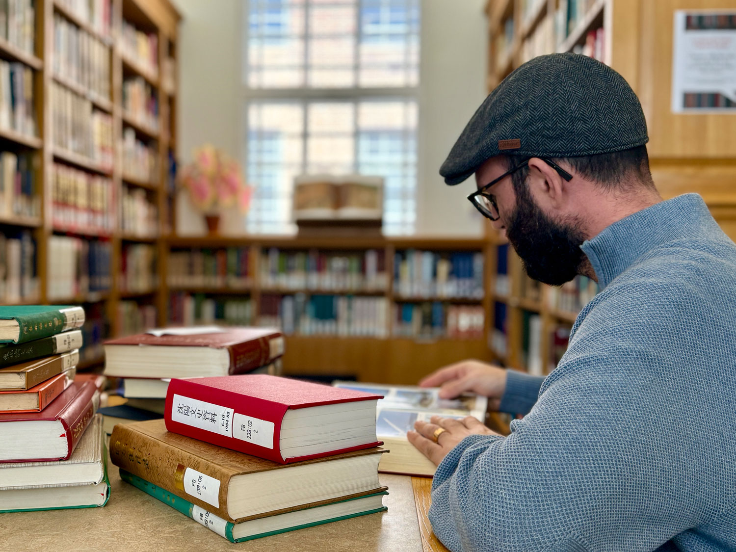 Ian Dubrowsky sitting at a desk browsing the Chinese Collection in the University Library.