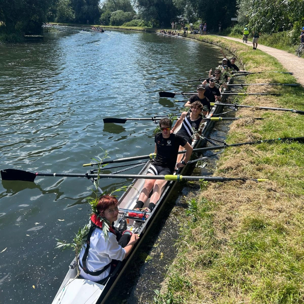 A boat of rowers pulled up by the river bank.