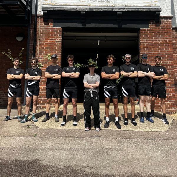 A group of rowers standing, arms crossed, outside the Boathouse.