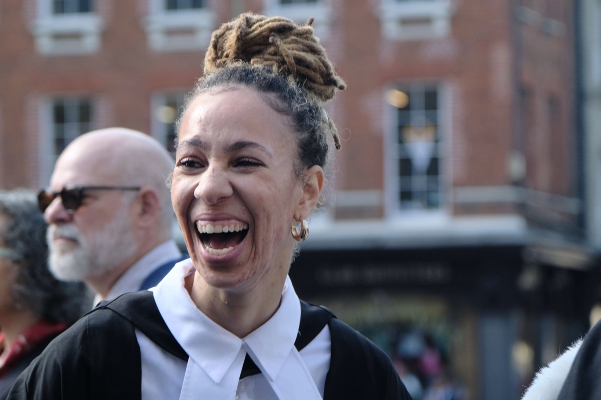 Student in academic dress laughing.